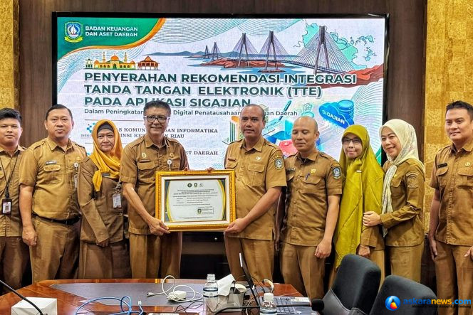 
 Sekretaris Diskominfo Kepri, James Simon Pattikawa menyerahkan Piagam Pengesahan Integrasi TTE Aplikasi SIGAJIAN kepada Kepala Bidang Perbendaharaan dan Pengelolaan Kas Daerah BKAD Kepri I Gede Sukanta, Selasa (4/8/2026).