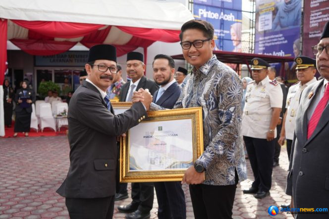 
 Kepala Kantor Wilayah Kementerian Hukum Aceh, Meurah Budiman menyerahkan penghargaan kepada Wakil Wali Kota Langsa, Muhammad Haikal Alfisyahrin, Rabu, 19 Agustus 2026. Foto: Humas.