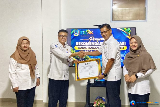 
 Sekretaris Diskominfo Kepri, James Simon Pattikawa didampingi Kepala Bidang Statistik dan Persandian Diskominfo Kepri Dwi Anggraini, menyerahkan Piagam Pengesahan Integrasi TTE Aplikasi SMART kepada Kepala DLHK Kepri Indra Hidayat, Kamis (22/10/2026). 